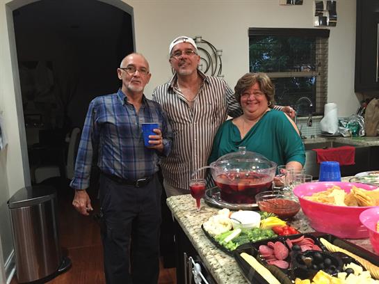 Friends celebrate together in the kitchen, sharing drinks and preparing food for a joyful gathering.