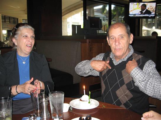 Two friends celebrate at a restaurant, enjoying food and drinks in a joyful moment.