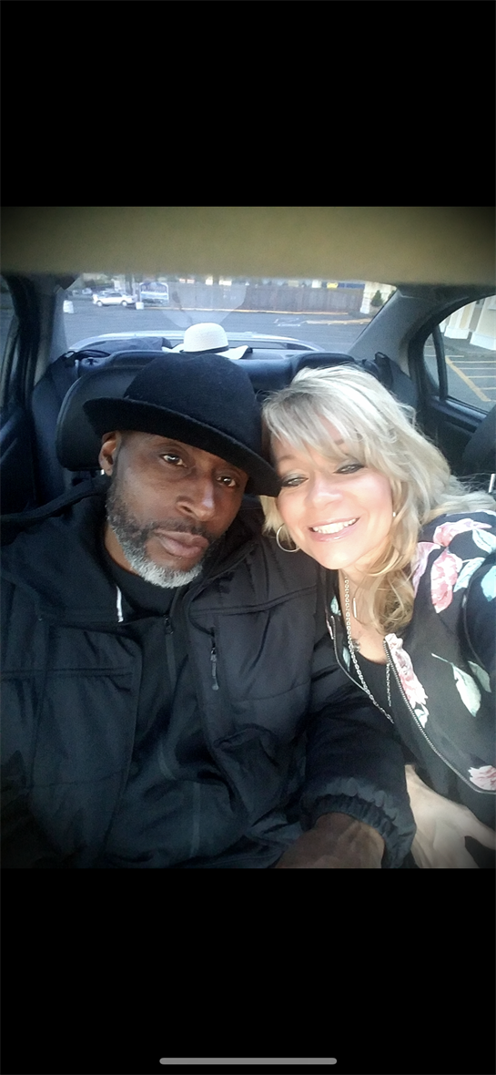 Man and woman smile warmly while seated inside a parked car, sharing a special moment.