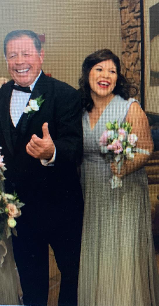 Happy couple in formal wear poses with flower bouquets at a celebration.