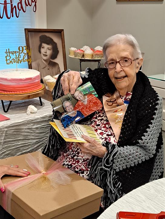 An elderly woman joyfully shares memories with family during her birthday celebration.