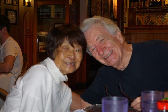 A cheerful couple enjoys their time together at a restaurant, smiling and engaging in conversation.