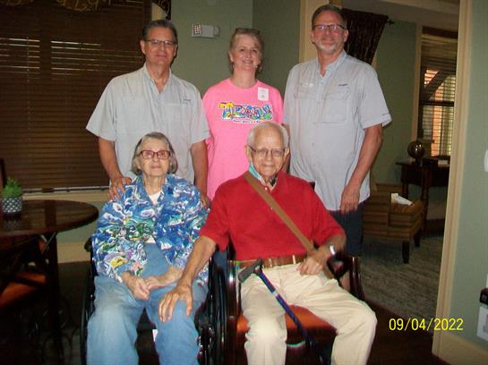 Family members gather together at a senior care home, sharing smiles and love for one another.