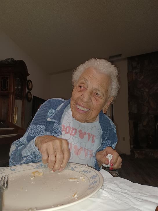 Smiling elderly man seated at a table, savoring a delicious meal while sharing stories.