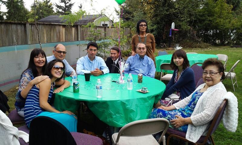 Group of family members enjoying a lively gathering outdoors at a backyard table on a warm day.