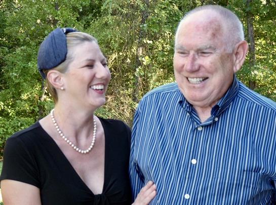 A woman and a man share laughter and happiness during a warm day in a beautiful outdoor environment.