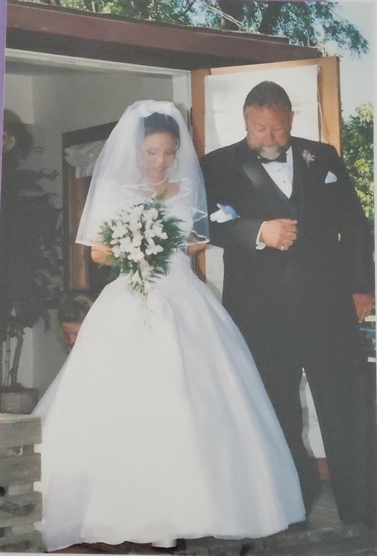 Bride in white dress holds bouquet while walking with her father before the wedding ceremony.