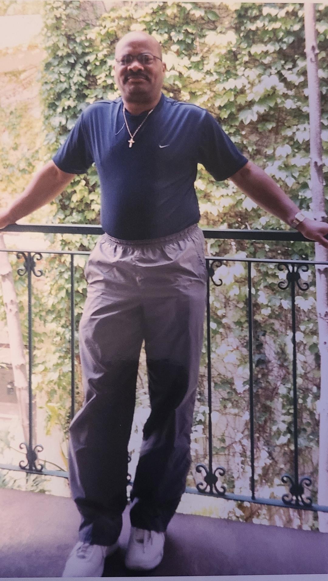 A person relaxes on a balcony surrounded by lush green vines on a sunny day.