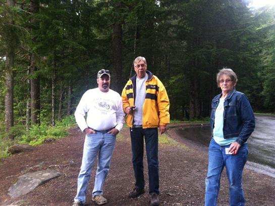 Friends gathered on a dirt path surrounded by trees, enjoying a casual outing in nature.