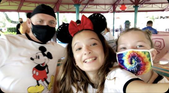 Families gather for a joyful moment at an amusement park, with kids dressed in fun costumes.