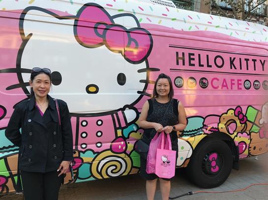 Two women stand by a colorful food truck, enjoying the lively city vibe.