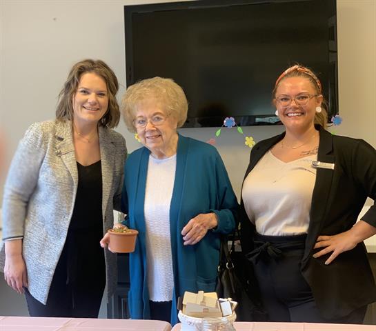 Women gather together indoors, sharing smiles and joy at a community event with plants involved.