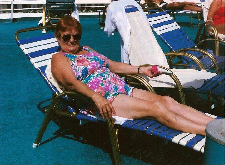 A woman enjoys her time lounging on a pool chair, savoring a snack in warm weather.