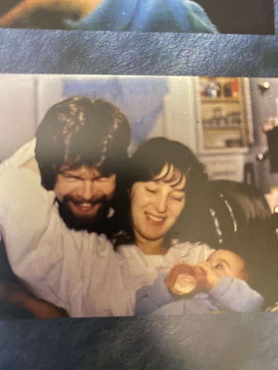 A smiling couple joyfully interacts with their baby, showcasing love in a warm living room.
