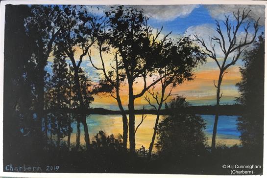 Vibrant colors of sunset reflect in the tranquil lake as silhouettes of trees frame the view.