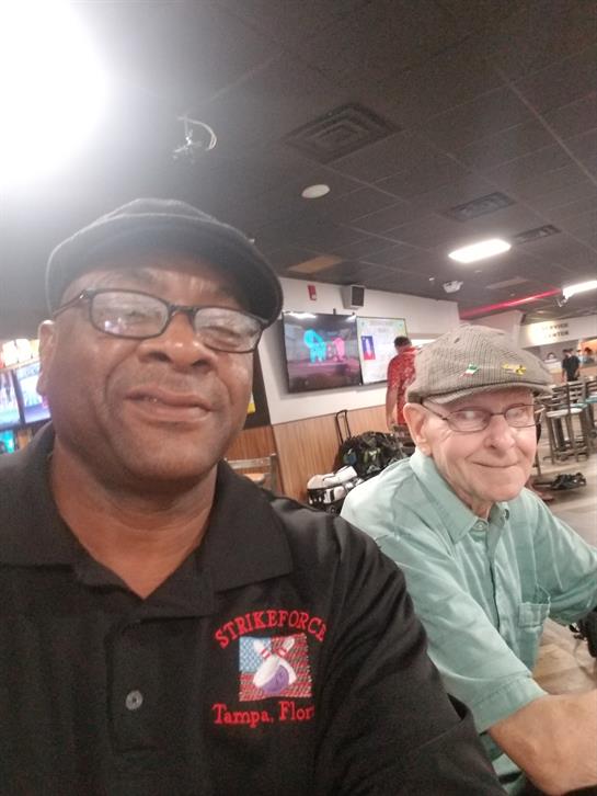 Two friends share a cheerful moment together at a bowling alley, immersed in conversation.