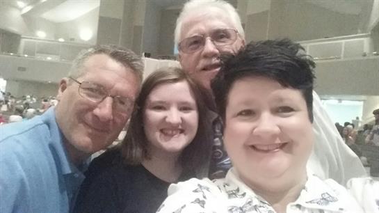 Four individuals pose together smiling, showcasing joy during a social celebration at a venue.