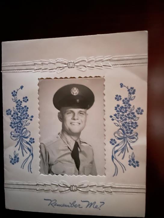 A smiling soldier poses in uniform within a decorative floral frame on cardstock.