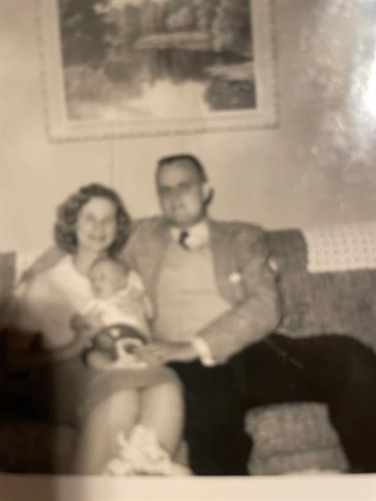 Parents are sitting on a couch with their baby in a warm and inviting living room atmosphere.