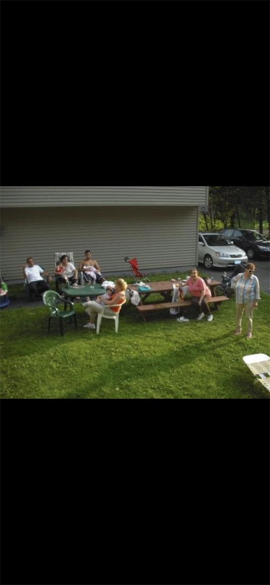 Group of people relaxing in a backyard, enjoying snacks and conversation on a sunny afternoon.
