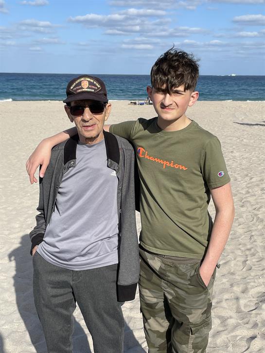 Grandfather and grandson enjoy a cheerful moment together on the beach by the ocean.