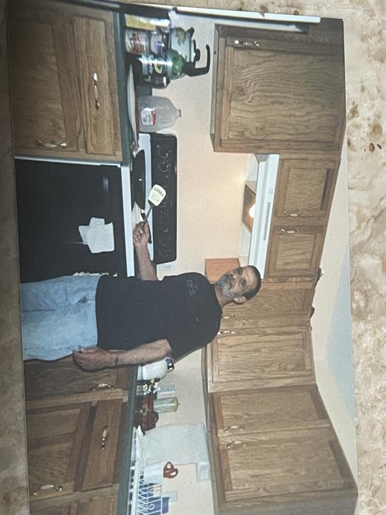 A man stands in a warm kitchen, preparing food and enjoying the cooking process.