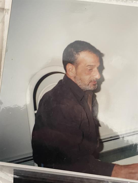 A man is seated casually, looking thoughtful, with soft light casting gentle shadows around him.