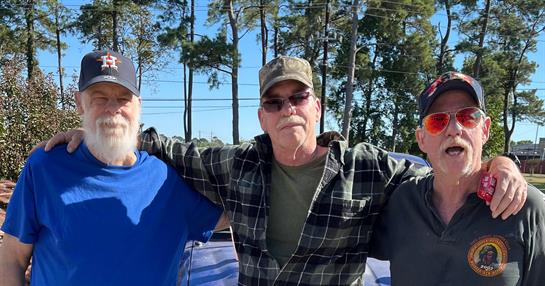 Two friends stand outdoors under a clear blue sky, smiling while enjoying a joyful moment together.