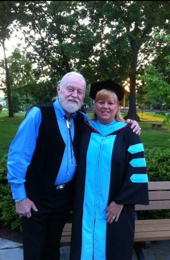 Friends celebrate in a park, proudly wearing graduation attire and sharing a joyful moment.