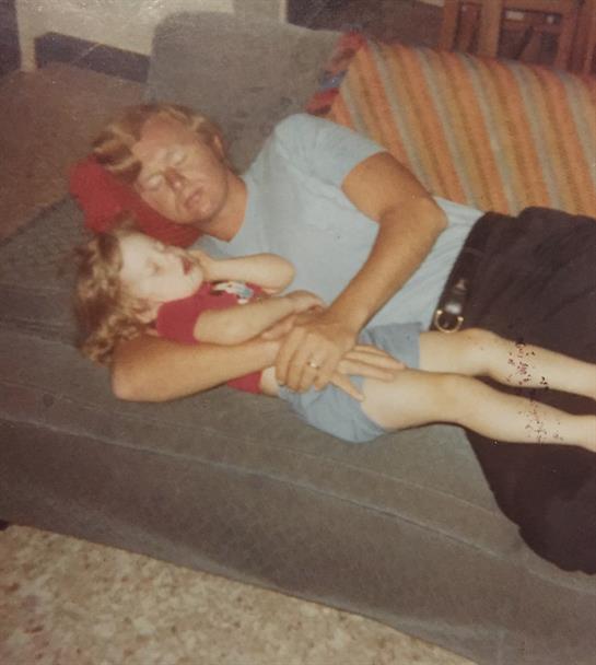 An elderly man and a young child relax together on a couch, enjoying a quiet afternoon.