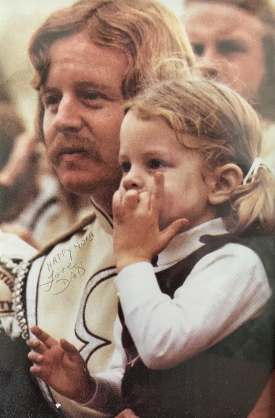 A man holds a child close as they share a lighthearted moment at a lively gathering.