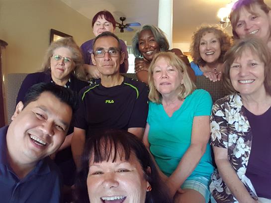 A group of friends smiles and poses together, celebrating a warm reunion at a home.