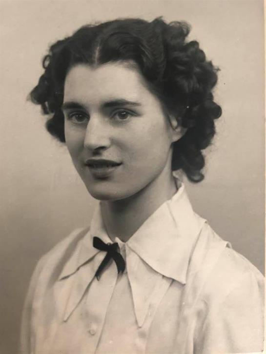 A young woman in a white shirt and black tie confidently models vintage fashion.