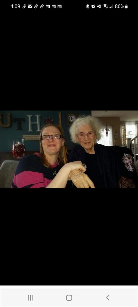 Two smiling women sit close together in a relaxed living room, sharing stories and laughter.