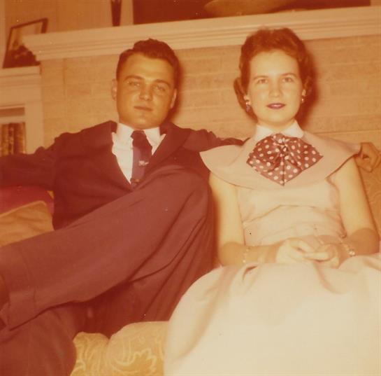 A couple relaxes on a couch, embodying timeless mid-20th century elegance.