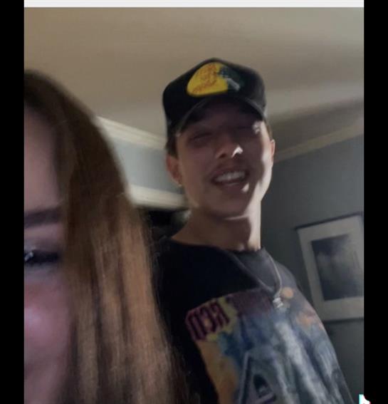 Two friends smile while capturing a lighthearted moment together indoors during a relaxed evening.