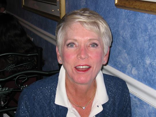 Woman enjoys a relaxed moment in a warm, inviting room, sharing a smile with friends.