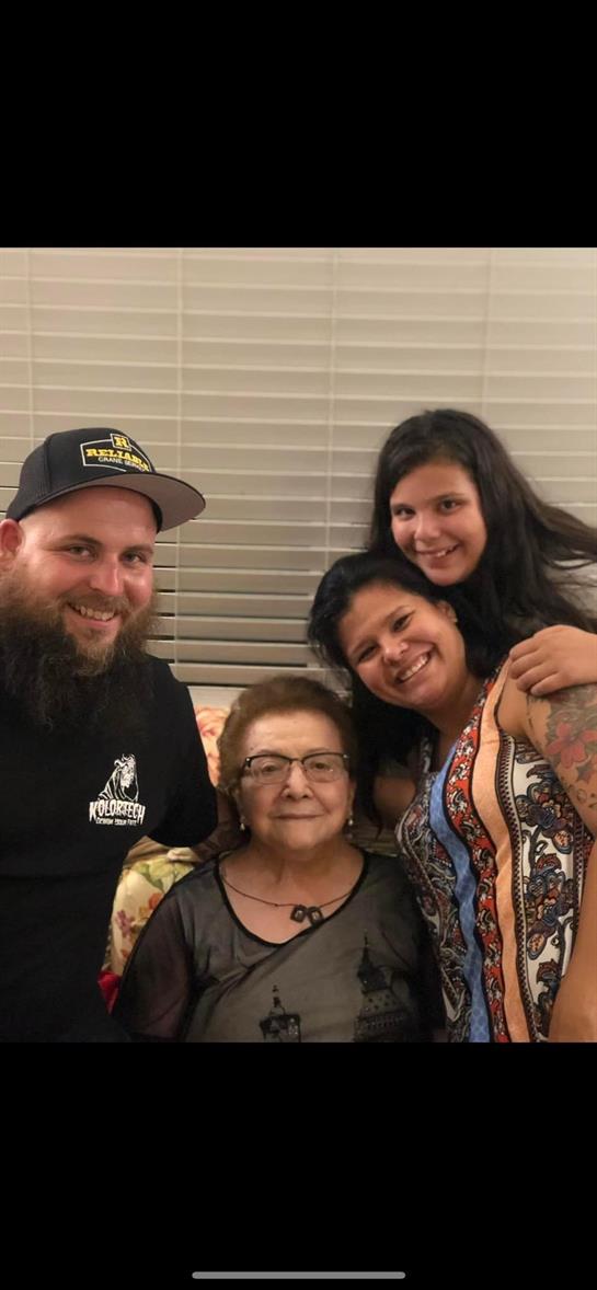 Four family members gather together in a living room, sharing smiles and affection at night.