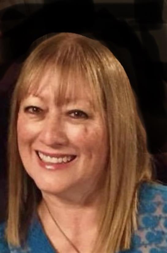 Woman with long hair smiles warmly at the camera during a festive gathering at night.