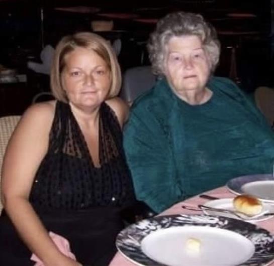 Two women sit at a table with empty plates, smiling in a restaurant environment during dinner.