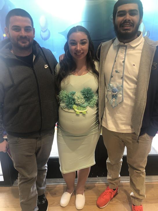 Close friends gather around a pregnant woman at a joyful celebration in an upbeat atmosphere.