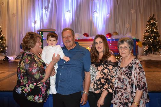 Five family members gather around a child, embodying joy and togetherness in a festive setting.