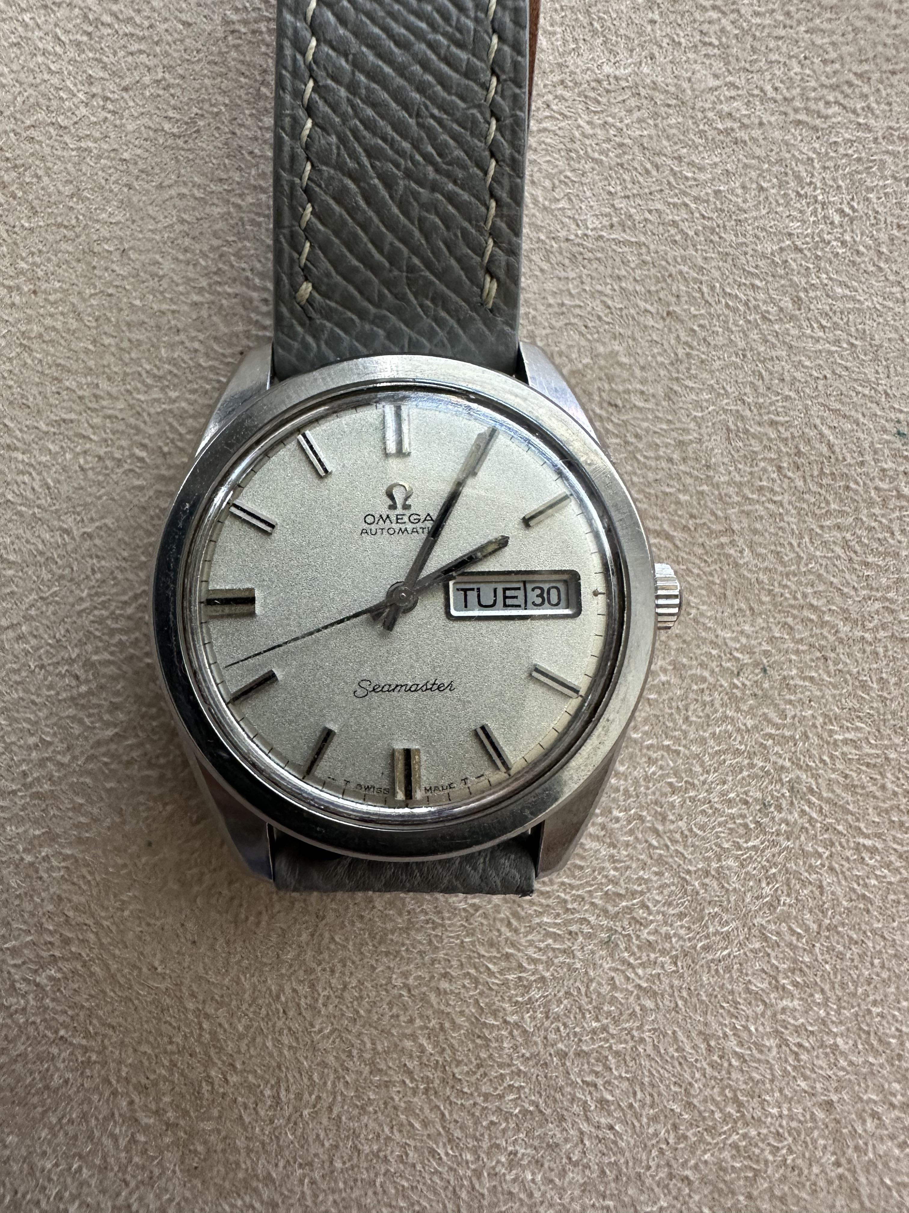 This watch has a silver face, day-date function, and a gray leather strap for elegance.