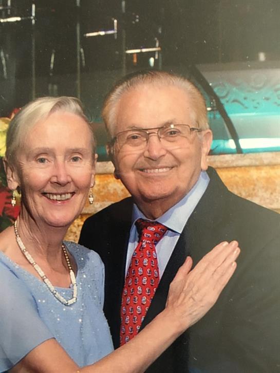 Elderly couple joyfully celebrates in a vibrant, decorated venue.