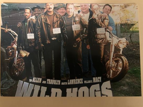 A group of friends, dressed in leather jackets, pose proudly with motorcycles on a sunny day.