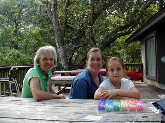 Three women sit together at a picnic table, enjoying time outdoors in a picturesque location.