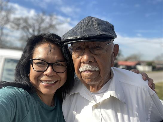 Two individuals pose happily together outdoors, enjoying a bright and sunny day in the park.