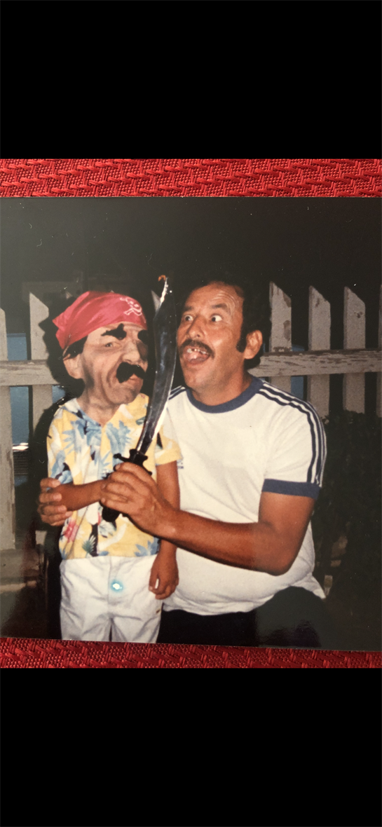A man and a child, both in pirate attire, are joyfully posing with a sword during a gathering.