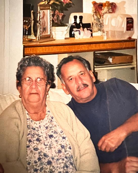 Elderly couple relax on a couch, sharing a warm moment in their cozy home.
