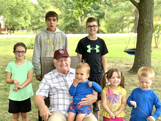 A group of children and adults are gathered in a park, smiling and enjoying quality time together.
